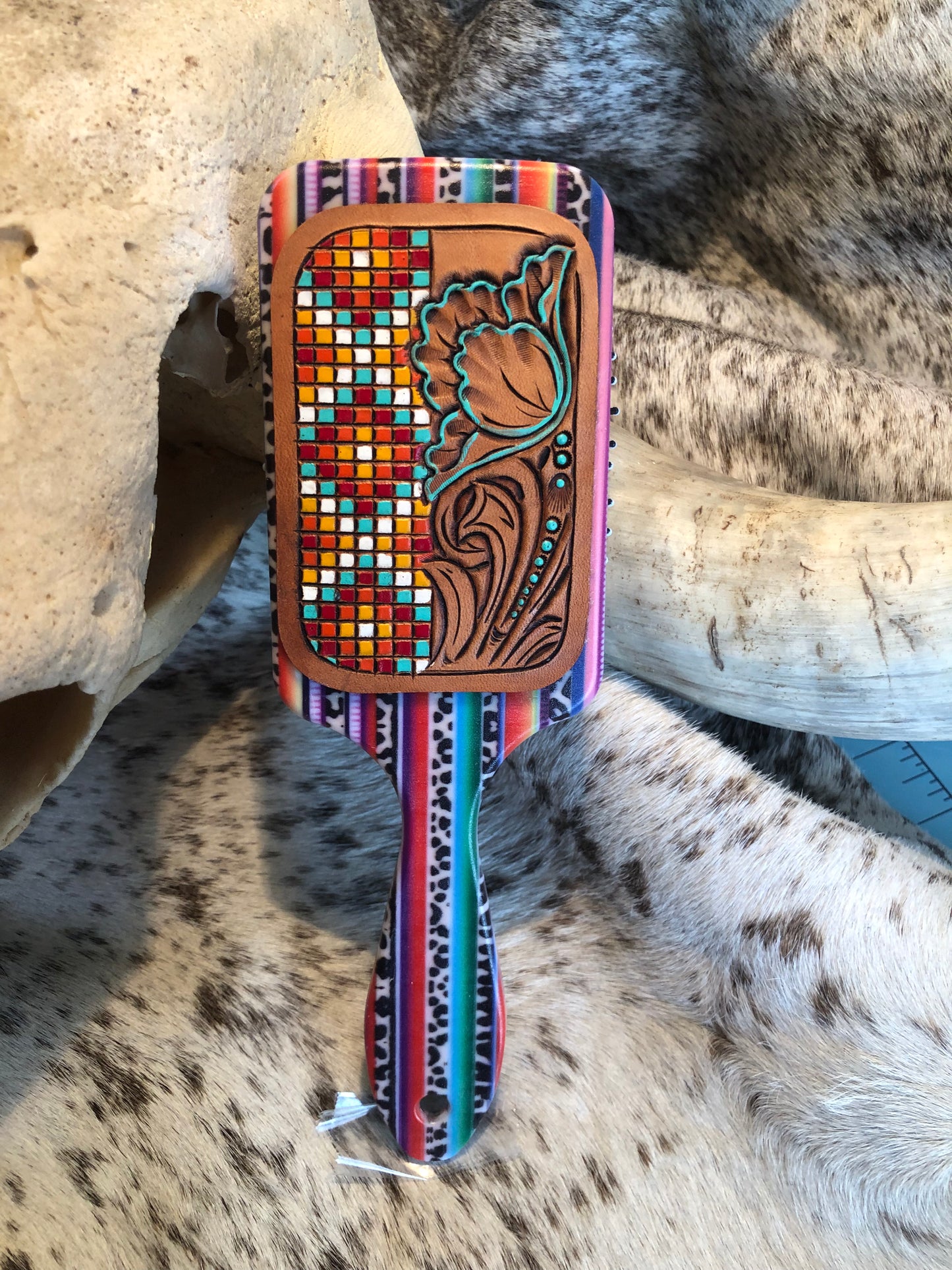 Western tooled leather floral and faux beadwork patch on serape print paddle brush