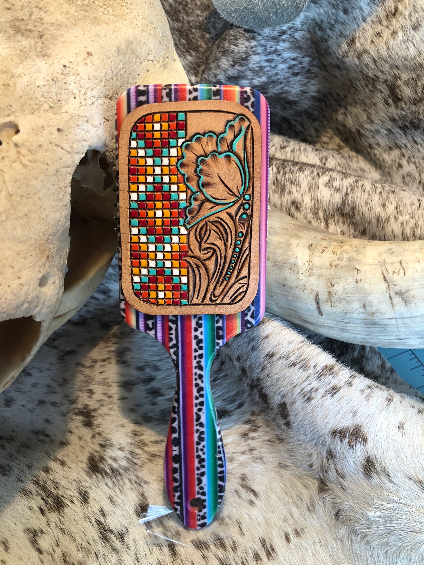 Western tooled leather floral and faux beadwork patch on serape print paddle brush